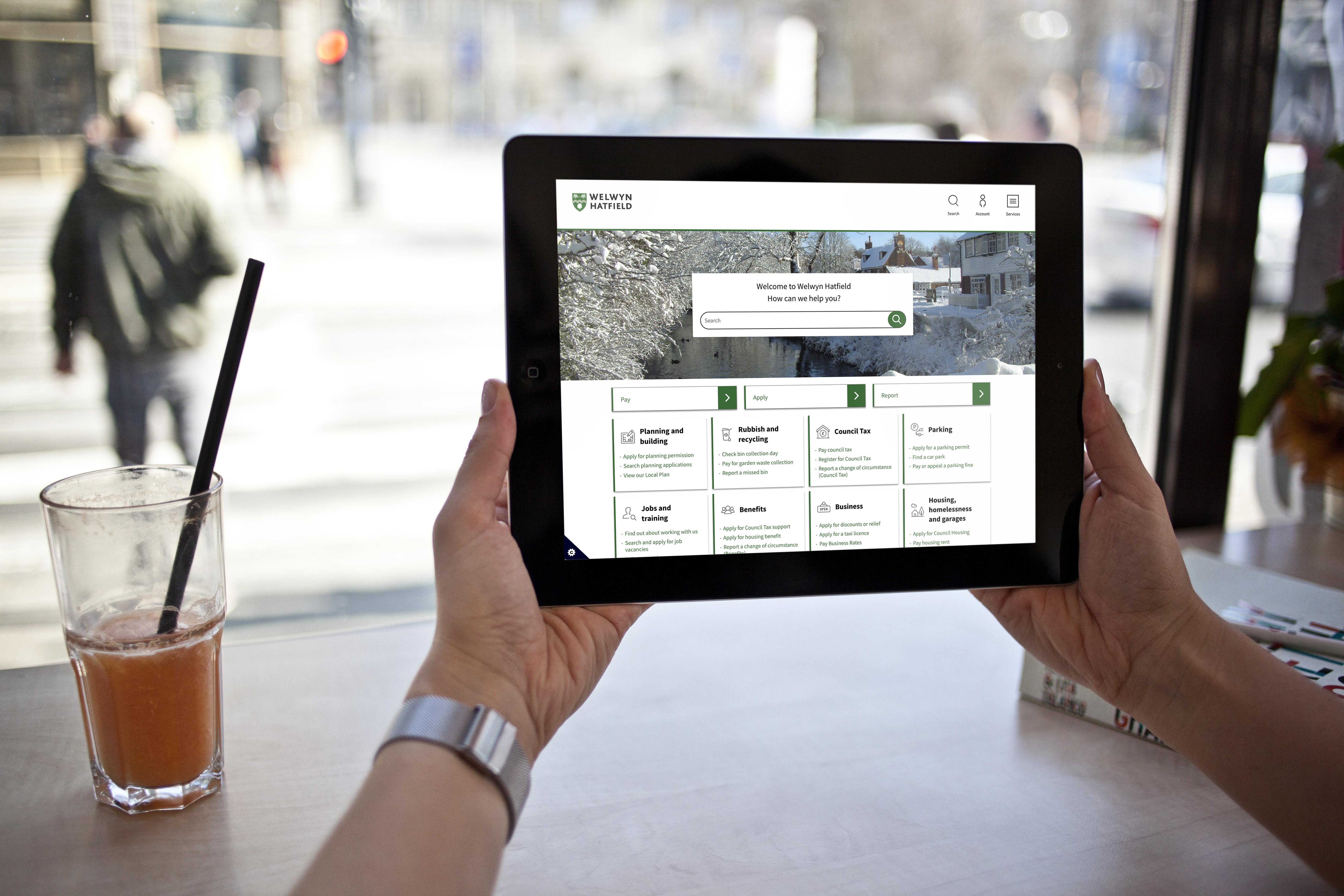 Welwyn hatfield website held up on a tablet in a coffee shop